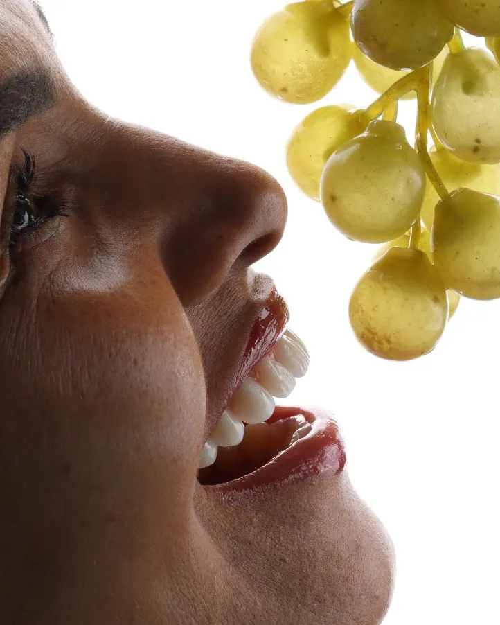 Paciente que viajou 650 km sorrindo de perfil, mordendo um cacho de uvas